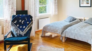 A bedroom with a bed, a chair with a blanket, a window with curtains, and a framed picture on the wall. - 2 Person Holiday Home in Ellos-by Traum (Ellos)