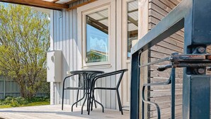 A wooden deck with a table and chairs, a window, and a metal railing. - 2 Person Holiday Home in Ellos-by Traum (Ellos)