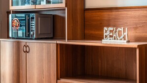 Un meuble en bois contenant un four à micro-ondes et une étagère en bois sur laquelle est posé un panneau indiquant « PLAGE ».