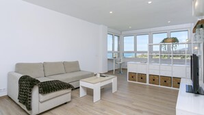 Una sala moderna con sofá, una mesa de centro y un balcón con vistas.