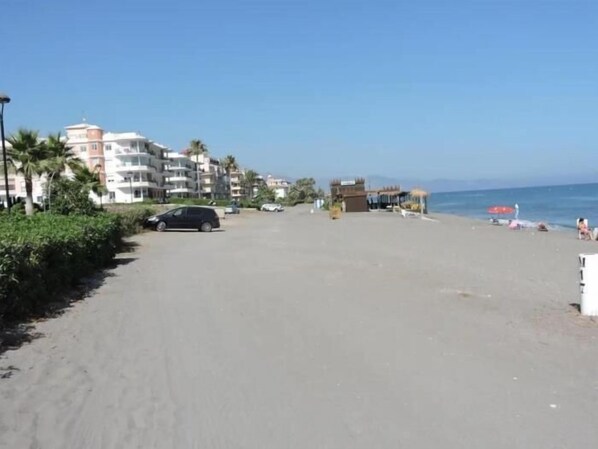 A beach with a parking area, buildings, and a clear sky. - Sunstay Guadalmar Loft Seaview (Málaga)