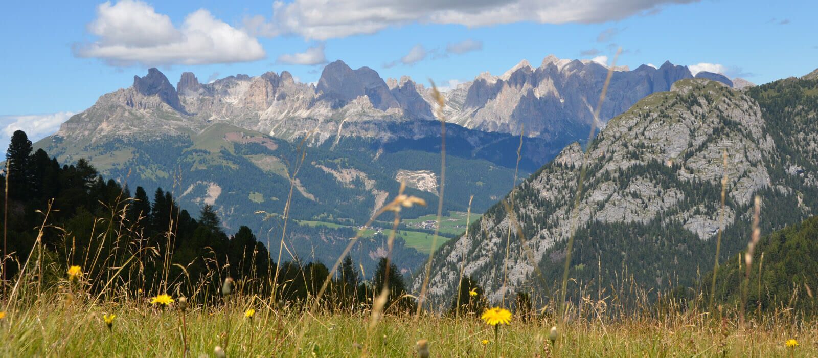 Un paysage montagneux avec une colline rocheuse bien visible au premier plan et une chaîne de montagnes en arrière-plan.