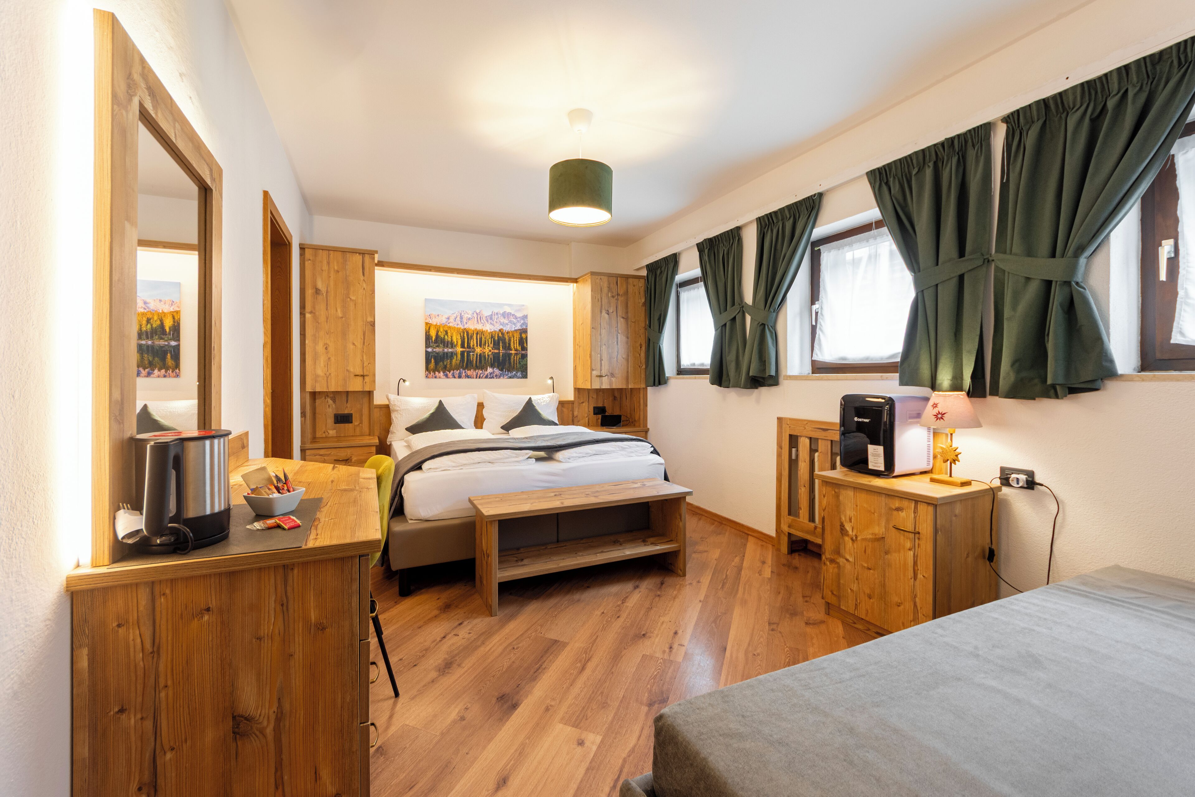 A bedroom with a bed, bedside table, lamp, and a painting on the wall.
