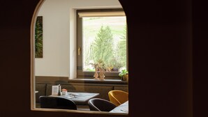 Ein Essbereich mit Tisch, Stühlen und einem Fenster mit Blick auf Bäume.
