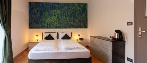 A modern bedroom with a large bed, bedside tables, a built-in bench, and a large forest-themed wall mural.