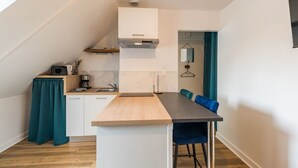 A compact kitchen with a central island, white cabinets, and a teal curtain. - Central and charming studio, Guingamp center (Guingamp)