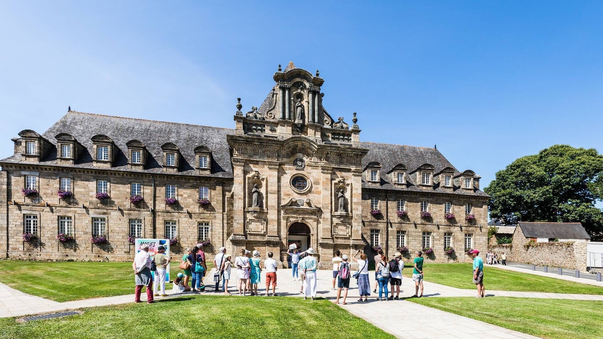 A historic building with a central entrance, multiple windows, and a statue on the roof.