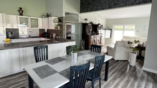 Una cocina moderna con armarios blancos, una isla central y un comedor con mesa y sillas.