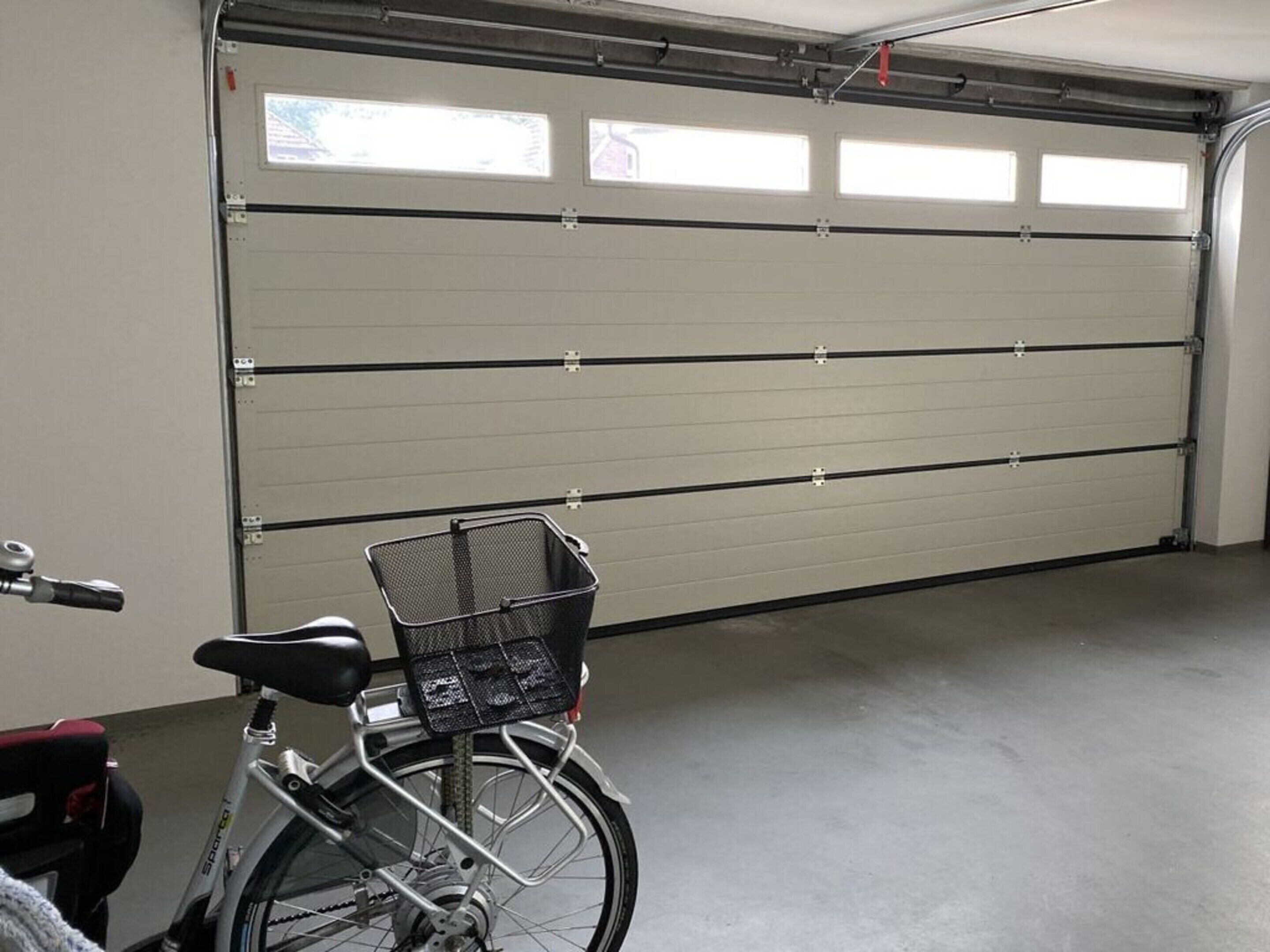Un vélo avec un panier est garé devant une porte de garage.