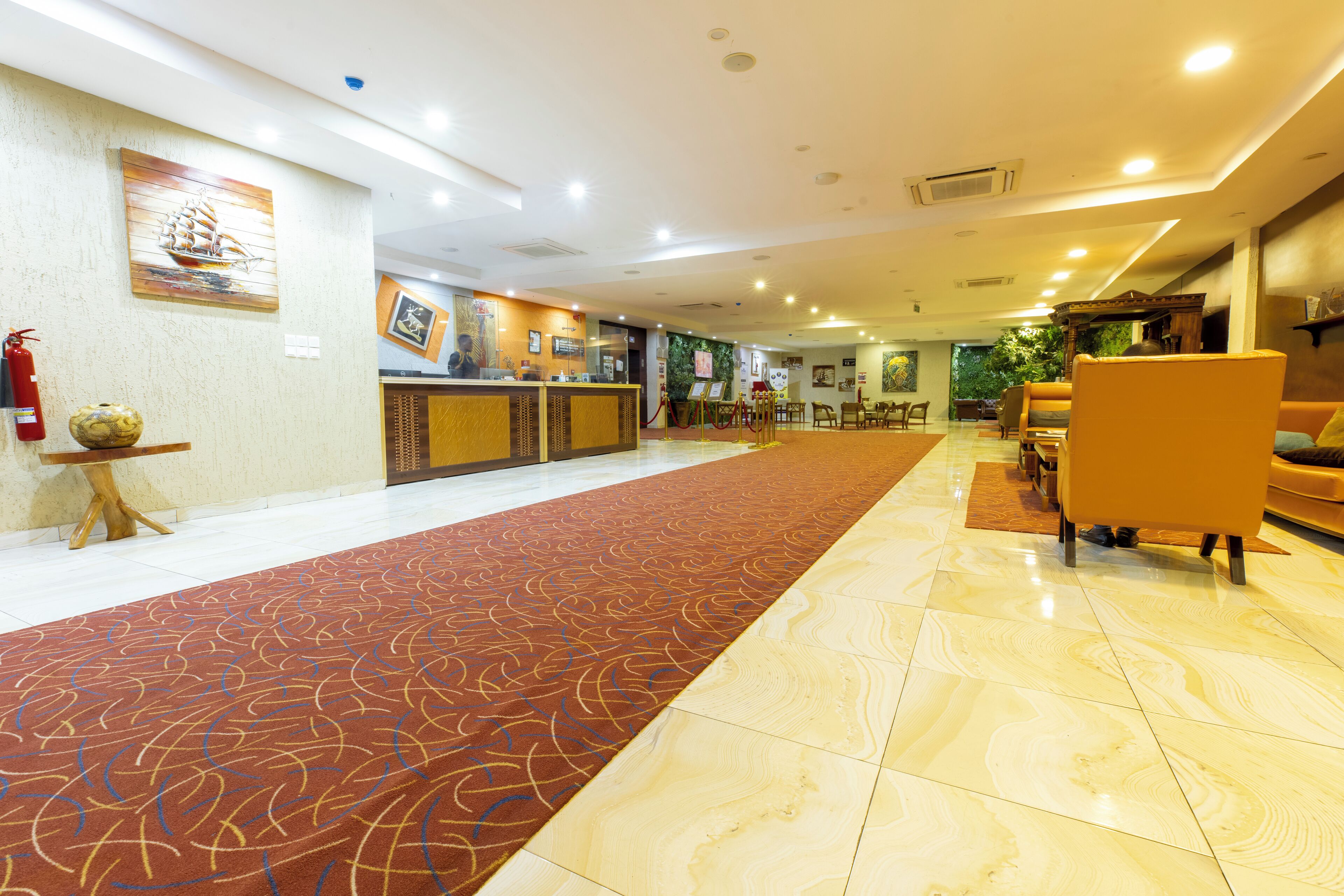 Vestíbulo de hotel con mostrador de recepción, zona de estar y alfombra estampada.