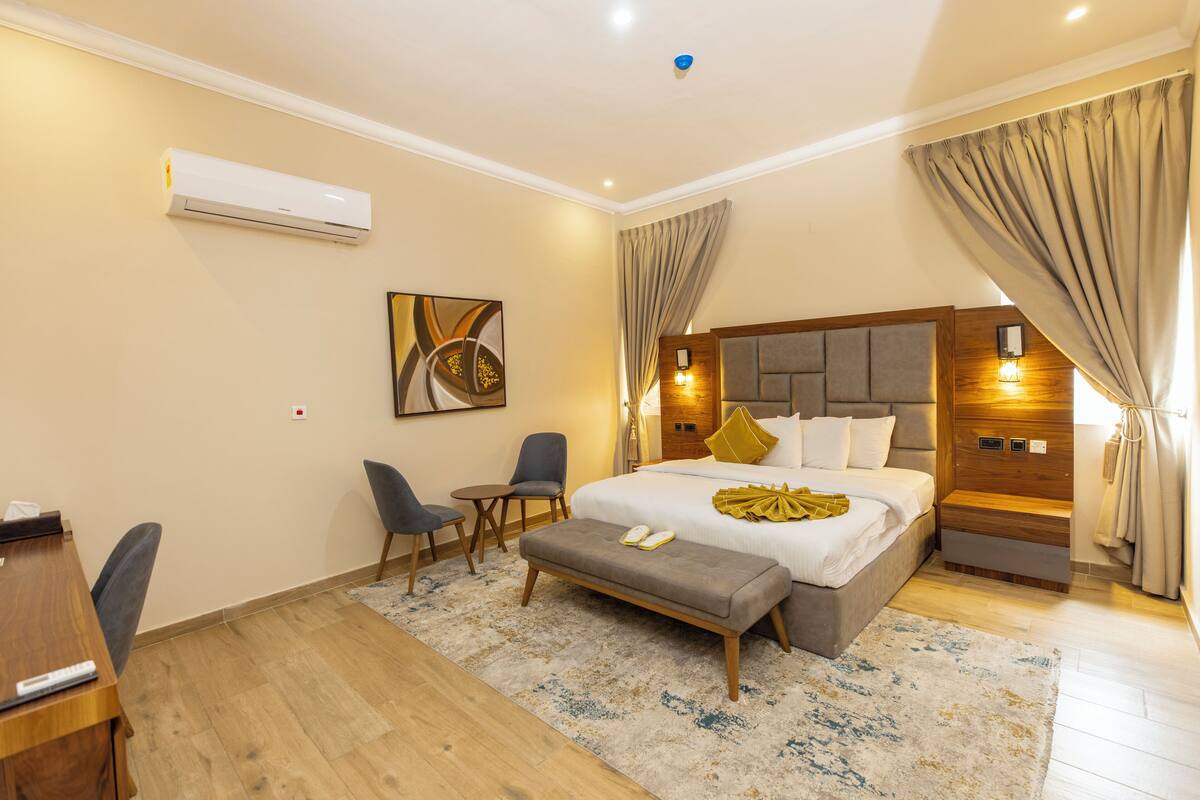 A hotel room with a bed, bedside tables, a desk, and a chair.