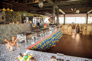 Un restaurante con una larga mesa de buffet, una barra con caja registradora y techo de madera.
