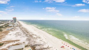 A beach with a tall building, clear skies, and a calm sea. - Beachfront!  Lazy River, Restaurant, New condo! (Orange Beach)