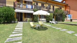 Ein gelbes Gebäude mit Balkon, Außenbereich und Garten.