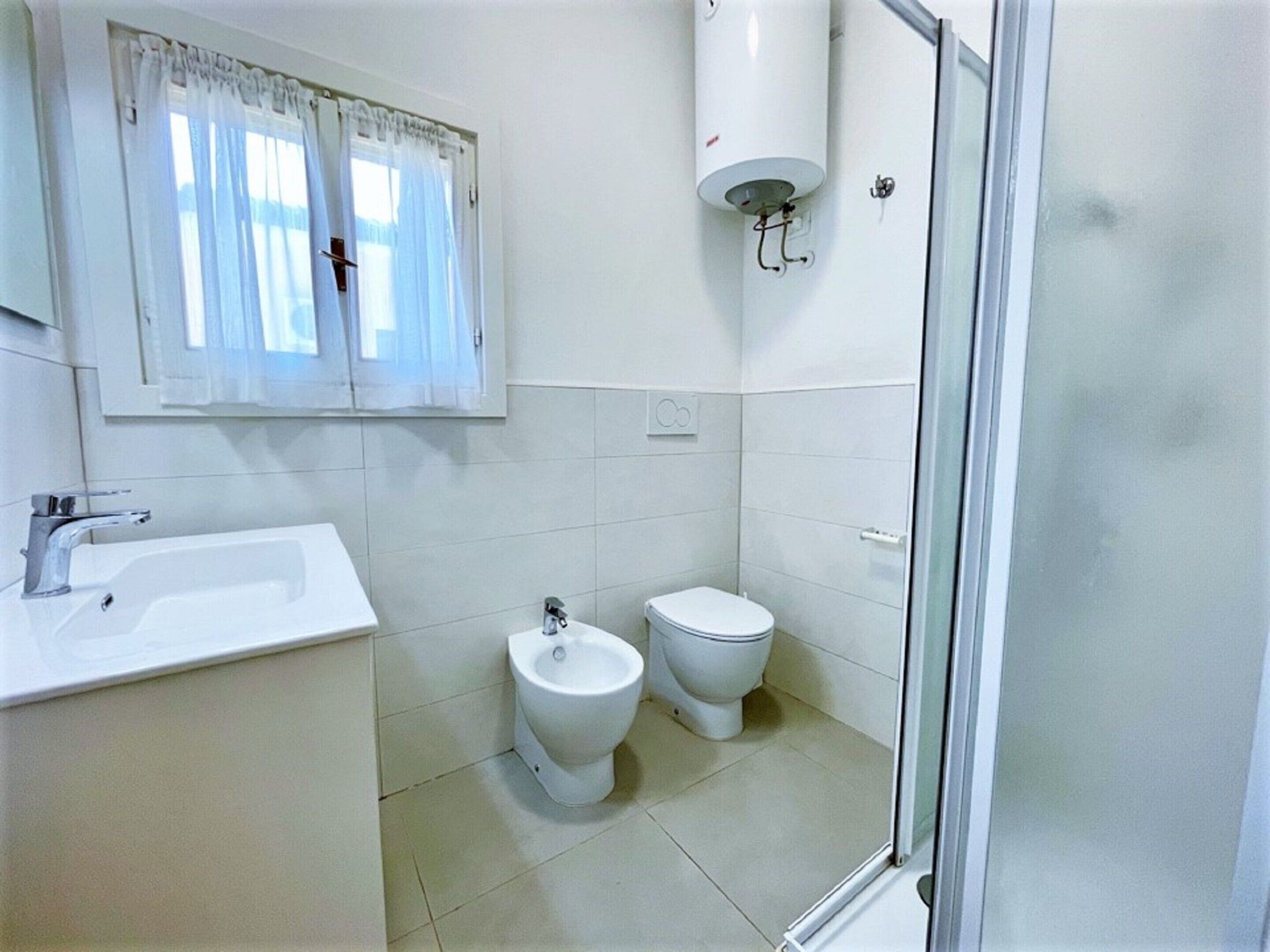A bathroom with a sink, bidet, toilet, and a shower area.