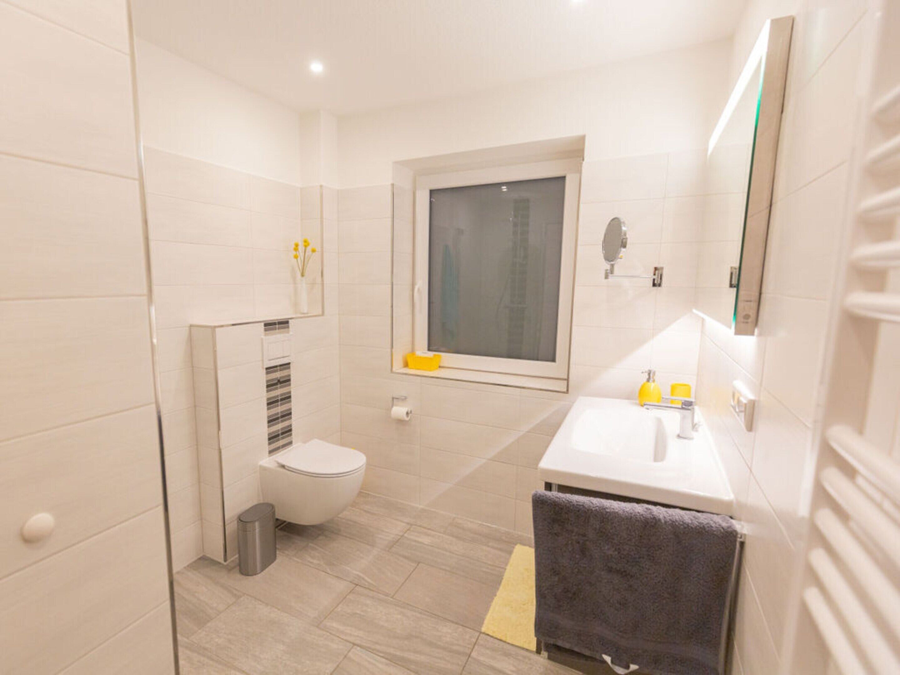 Et moderne badeværelse med toilet, håndvask og vindue.