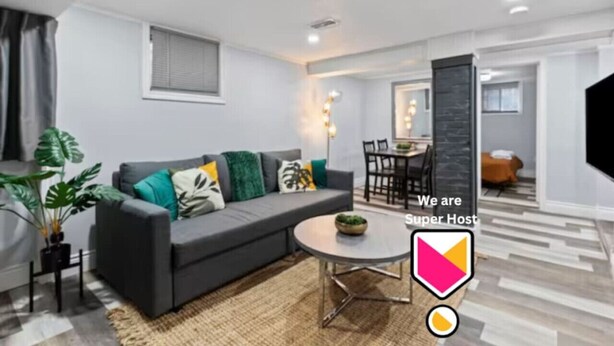 A modern living room with a grey sofa, a round coffee table, and a dining area with a black table and chairs.