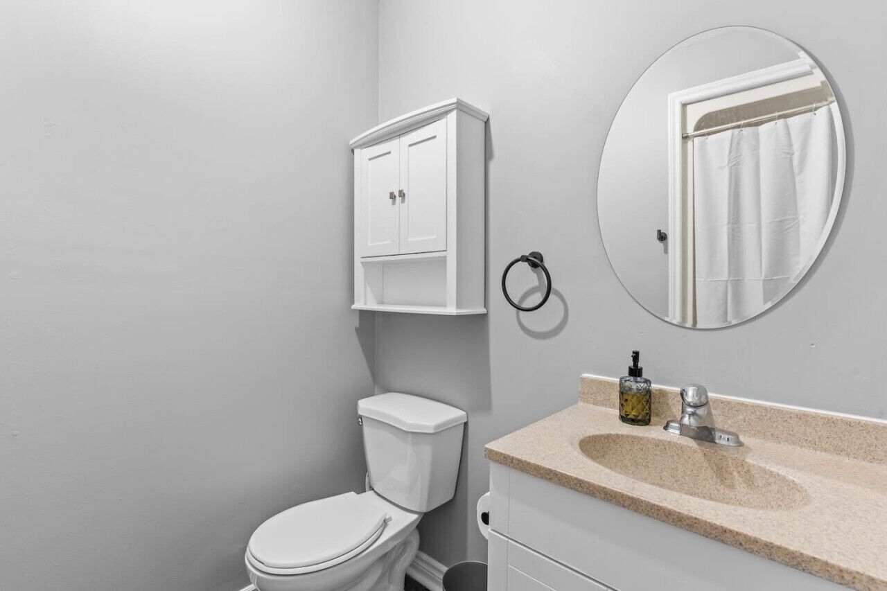 Een badkamer met een toilet, een wastafel met spiegel en een kastje.