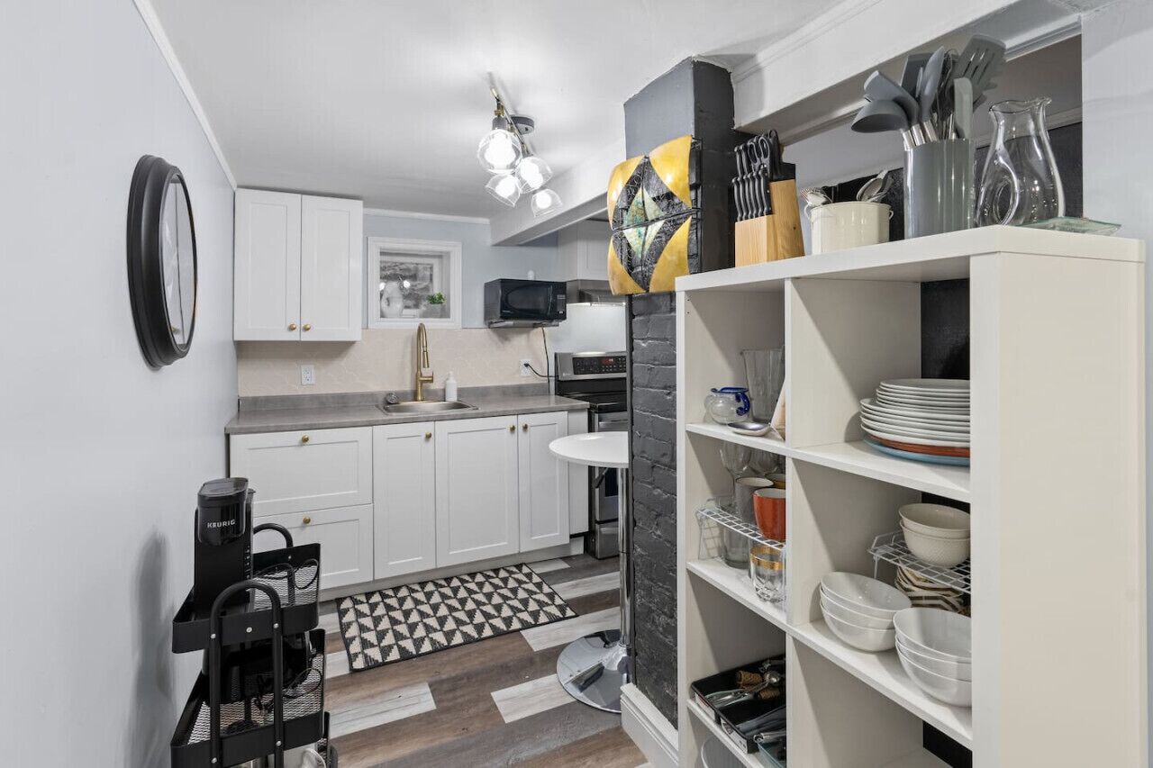 A compact kitchen with white cabinets, a black coffee machine, a microwave, and a sink.