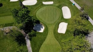 An aerial view of a golf course with sand bunkers, a water hazard, and a well-maintained green. - Stylish 2bd  DT Laundry and Parking (Windsor)