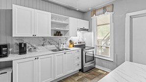 A modern kitchen with white cabinetry, a marble backsplash, and stainless steel appliances. - Stylish 2bd  DT Laundry and Parking (Windsor)
