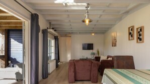 Un vaste espace de vie doté d’un plancher en bois, d’un canapé, d’une table à manger et d’un téléviseur fixé au mur.