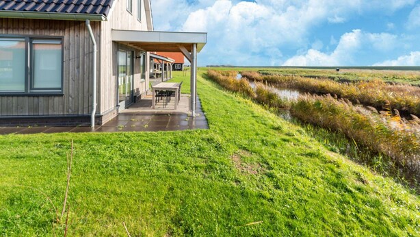 A modern house with a large patio, a solar panel on the roof, and a view of a marshy landscape. - Holiday Home in Scherpenisse Near Nature Reserve (Scherpenisse)