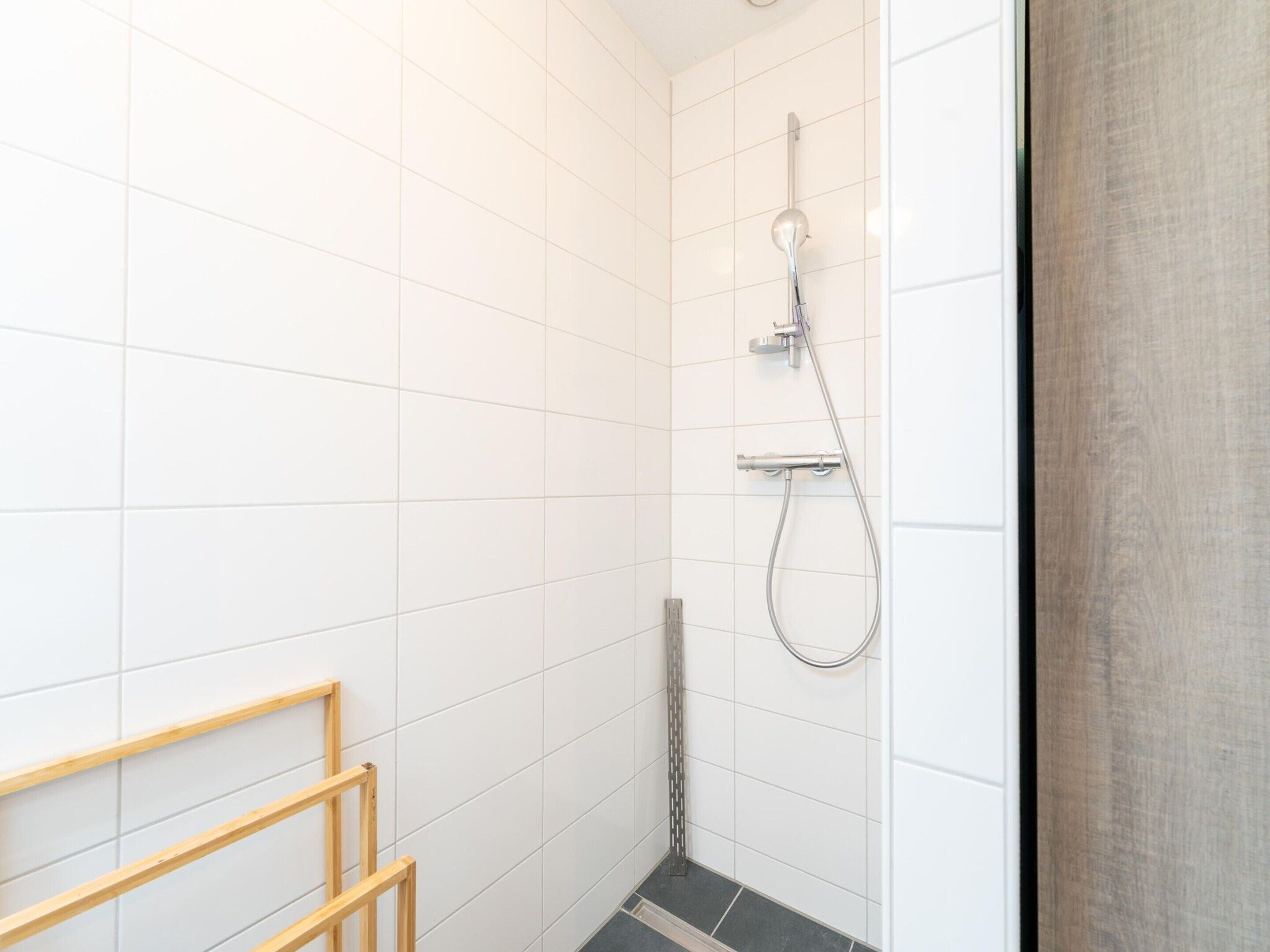 A small, tiled shower area with a showerhead and handheld shower attachment.