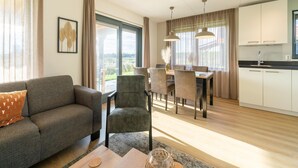A modern living room with a sofa, chairs, a dining table, and a kitchen area with white cabinets and a black countertop. - Holiday Home in Scherpenisse Near Nature Reserve (Scherpenisse)