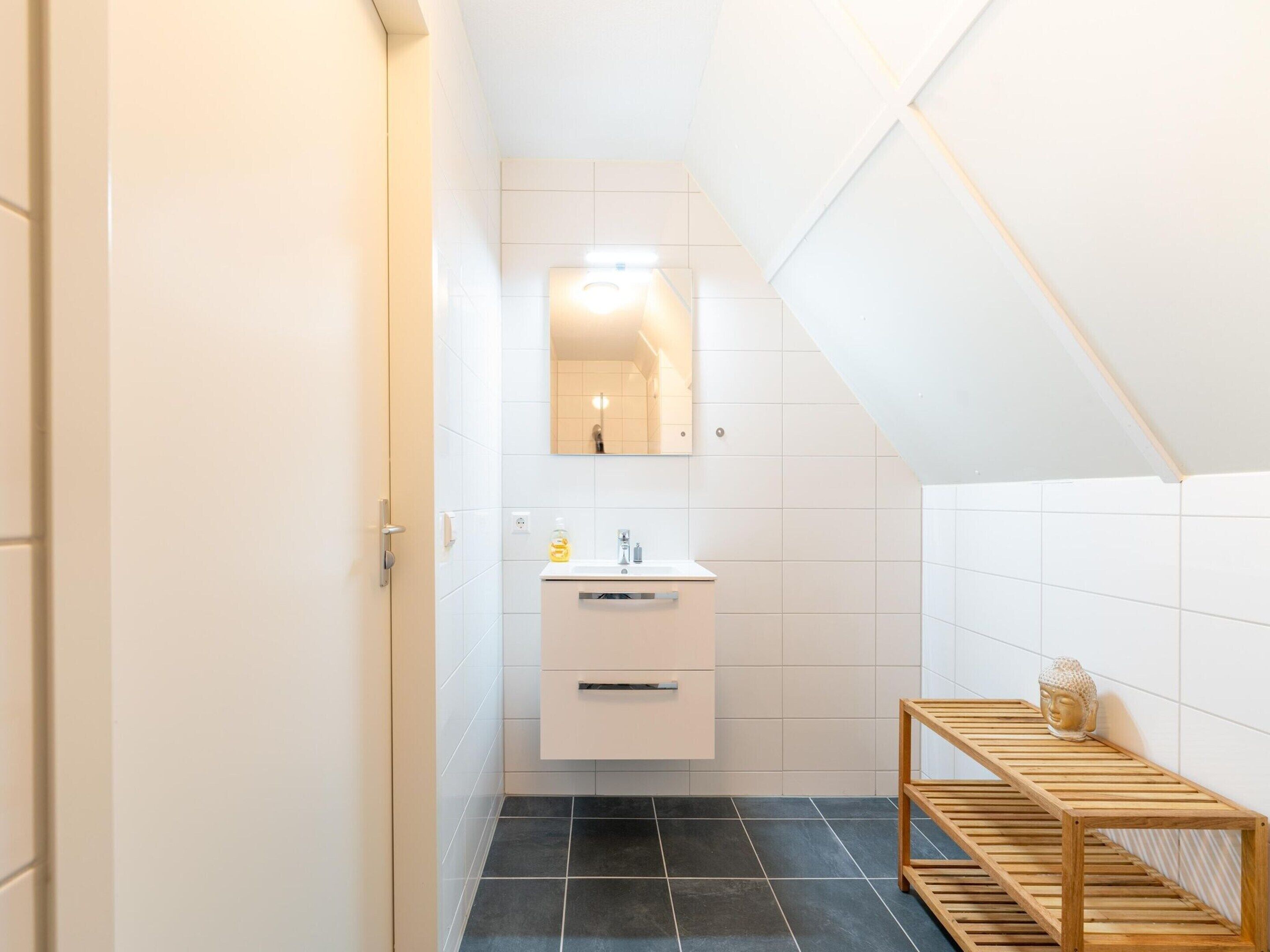 Une salle de bain moderne avec un meuble-lavabo blanc, un miroir et une étagère en bois.