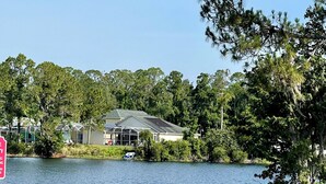 A lakeside view with a bench and a house in the background. - FREE Disney Plus & Hulu ~ 4 BR/2 BA Heated Pool Home 9mi to Disney Theme Parks (Davenport)