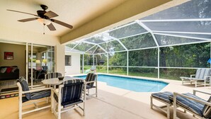 A covered outdoor area with a pool, seating, and a ceiling fan. - FREE Disney Plus & Hulu ~ 4 BR/2 BA Heated Pool Home 9mi to Disney Theme Parks (Davenport)