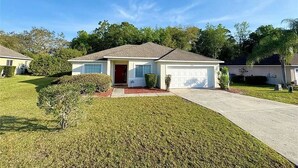 A single-story house with a garage, a front lawn, and a clear blue sky. - FREE Disney Plus & Hulu ~ 4 BR/2 BA Heated Pool Home 9mi to Disney Theme Parks (Davenport)