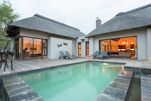A modern house with a pool, two lounge chairs, and a dining area. - Luxury Villa With a Swimming Pool in Hoedspruit (Hoedspruit)