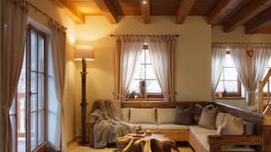 A cozy living room with a wooden ceiling, a sofa, a table, and a lamp. - Brocken Chalet No. 19 (Ilsenburg)