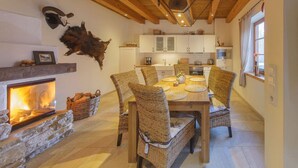 A cozy dining area with a fireplace, wicker chairs, and a stone fireplace surround. - Brocken Chalet No. 19 (Ilsenburg)