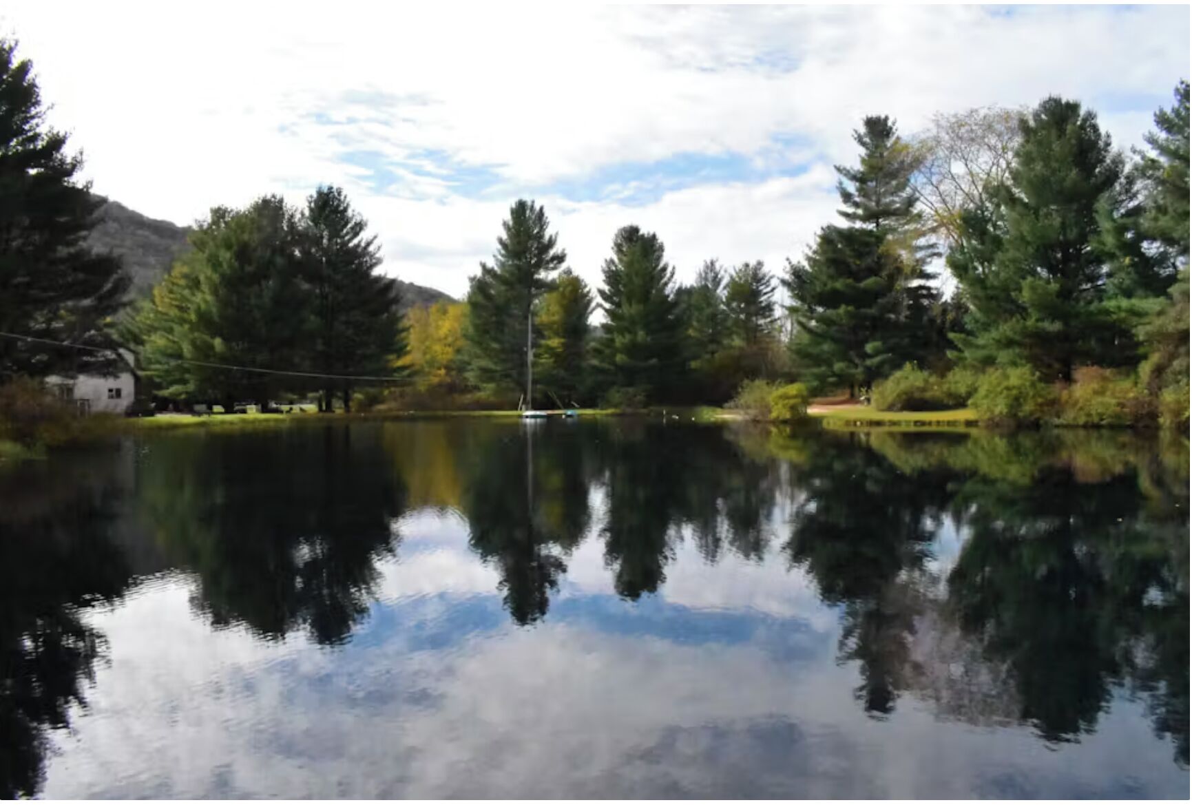 A calm lake with reflections of trees and a clear sky.