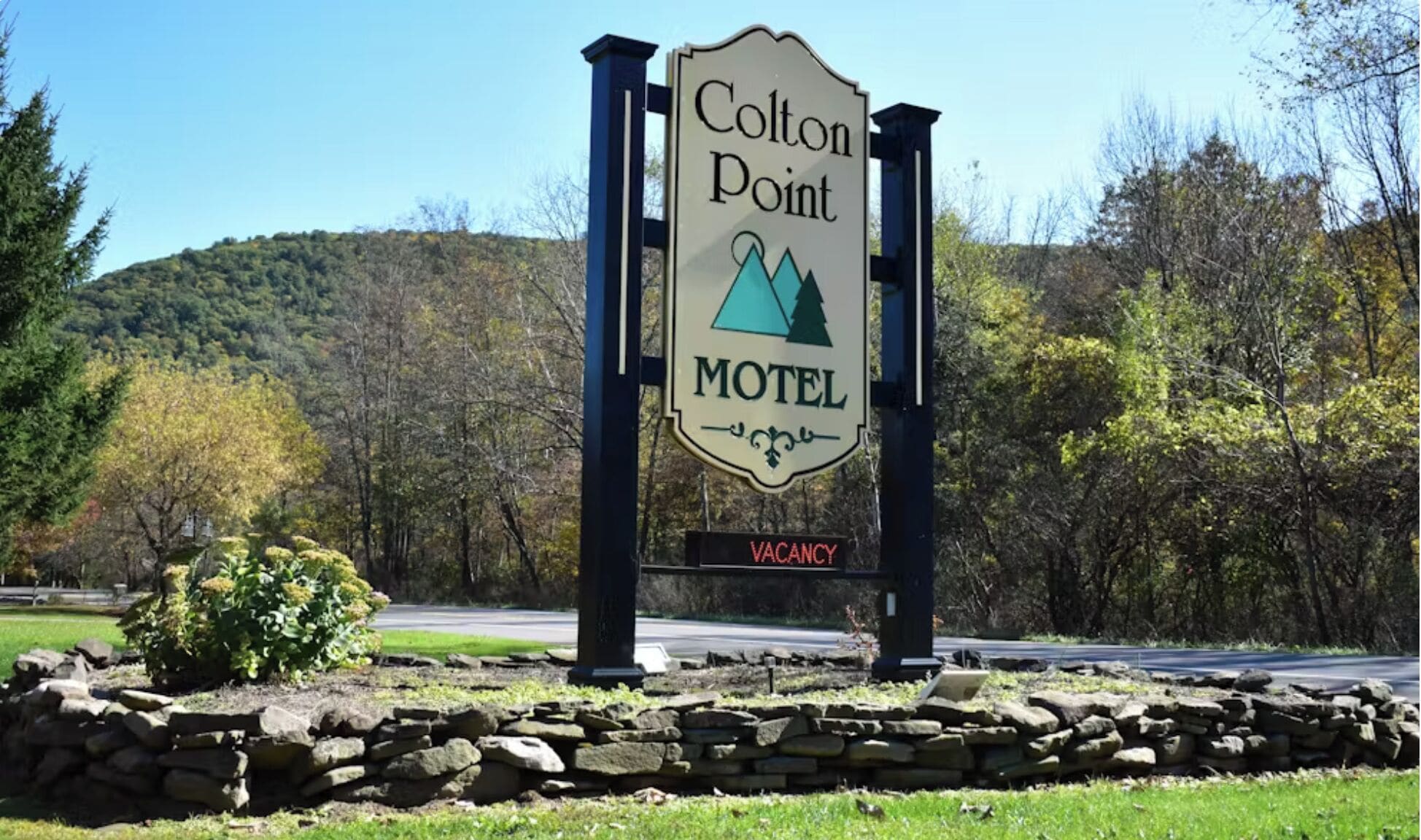 A motel sign with a mountain and tree logo, and a vacancy sign.
