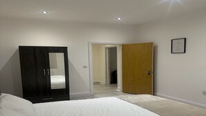 Ein Schlafzimmer mit einem Bett, einem Kleiderschrank und einer Tür zu einem anderen Raum.
