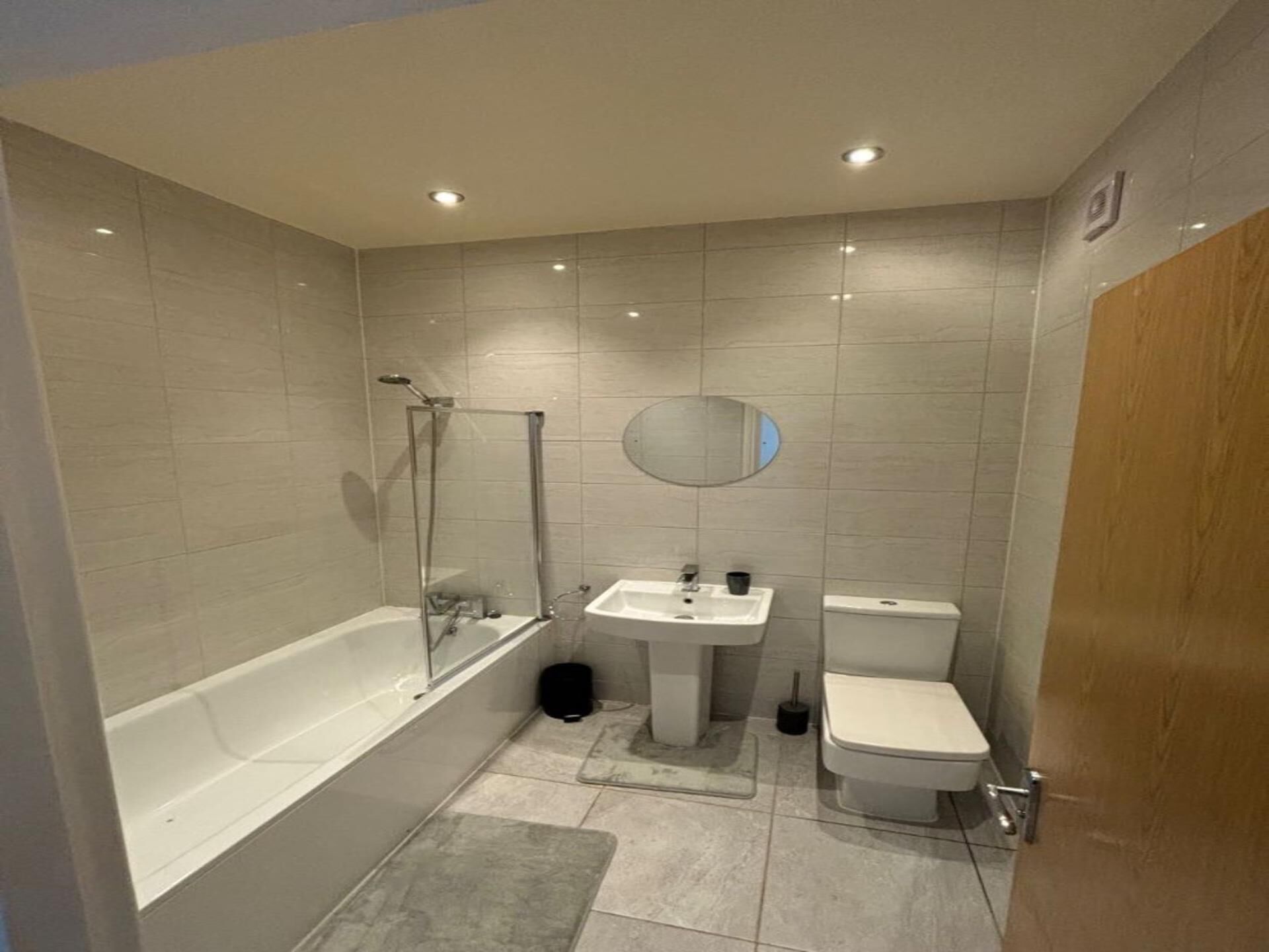 Un baño moderno con bañera, lavabo, inodoro y cabina de ducha de vidrio.