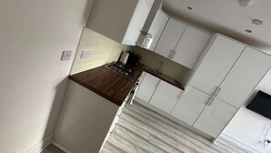 Una cocina moderna con armarios blancos, una encimera de madera y un salpicadero de mármol.