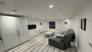 Una sala de estar moderna con un sofá gris, una mesa de centro y un televisor montado en la pared.