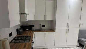 A modern kitchen with white cabinets, a gas stove, a microwave, and a sink. - Immaculate 1-bed Apartment in Walton on the Naze (Walton on the Naze)