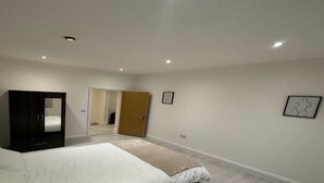 A bedroom with a bed, a wardrobe, a door leading to another room, and a framed picture on the wall. - Immaculate 1-bed Apartment in Walton on the Naze (Walton on the Naze)