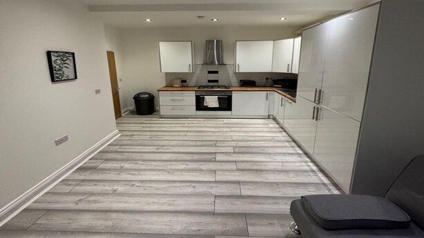 A modern kitchen with white cabinets, a wooden countertop, and a stainless steel range hood. - Immaculate 1-bed Apartment in Walton on the Naze (Walton on the Naze)