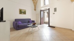 A living room with a purple sofa, a glass coffee table, and a painting on the wall. - 3910 Casa Nanà by Barbarhouse (Nardò)