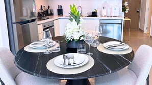 Une table à manger dressée pour quatre personnes, agrémentée d’un arrangement floral central, et entourée de chaises.