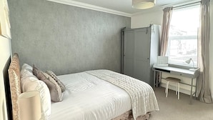 Un dormitorio con cama, escritorio y ventana.