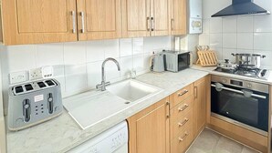 Una cocina moderna con armarios de madera, lavavajillas integrado, microondas, tostadora y estufa.