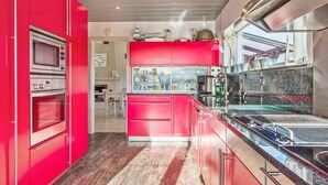 A modern kitchen with red cabinetry, stainless steel appliances, and a wooden floor. - Villa Near Sea and Shops in Belgium (Koksijde)